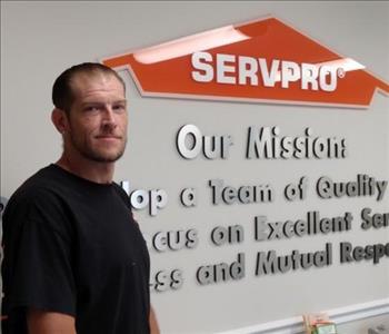 Man standing beside the SERVPRO logo on wall
