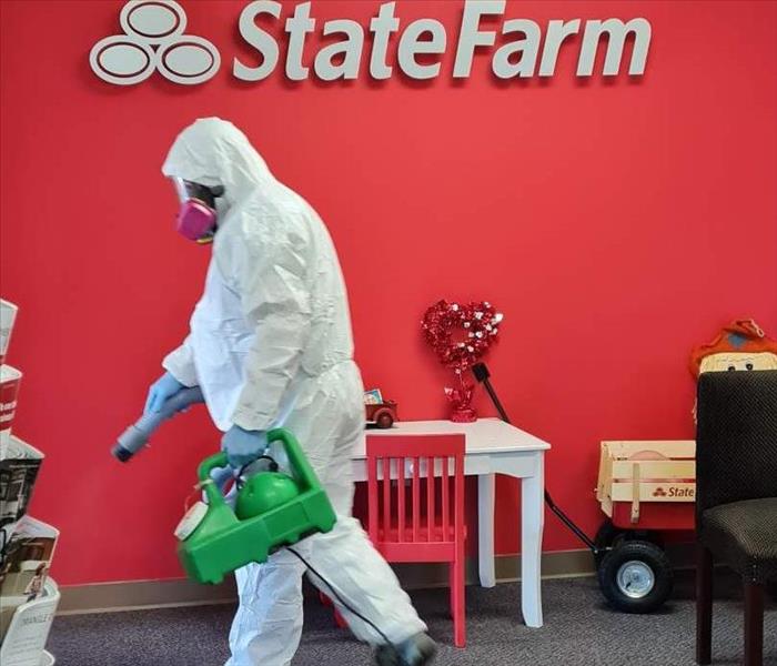 Man dressed in tyvek suit fogging a business for covid