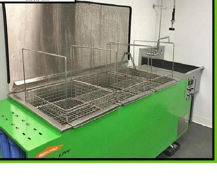 Square machine with a metal basket in it with liquid for cleaning
