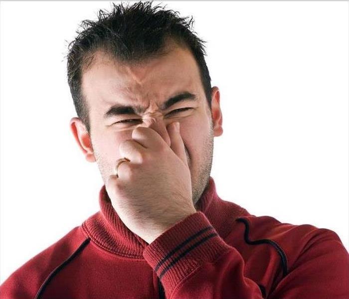 Man plugging nose and making a face because something stinks