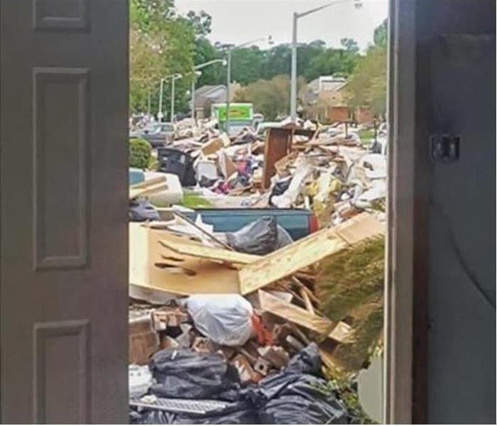 Looking through a door into the street piled high with debris after flood waters